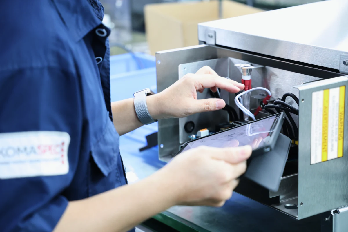 Komaspec technician inspecting a wire harness at an electrical test station