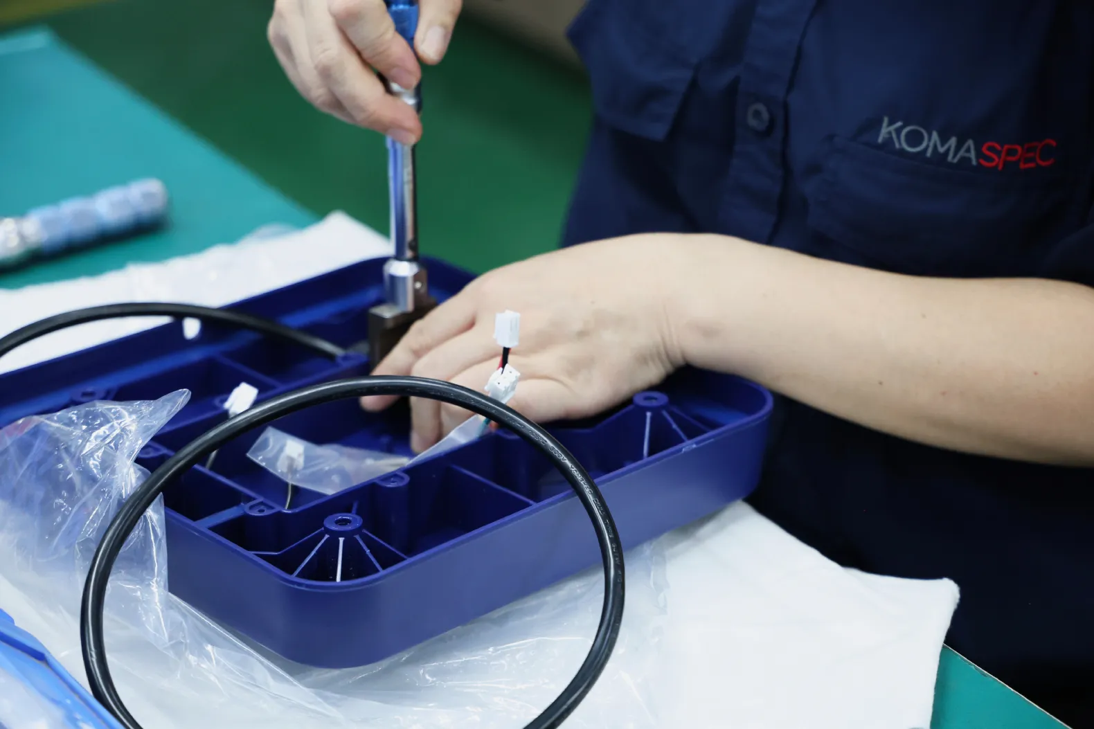 Komaspec technician assembling a molded plastic housing with a rubber gasket