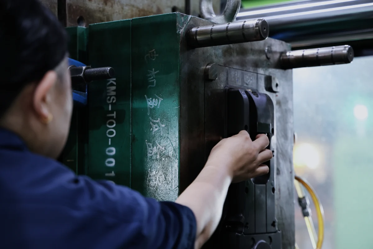 Technician placing a metal insert into an injection mold cavity during insert molding