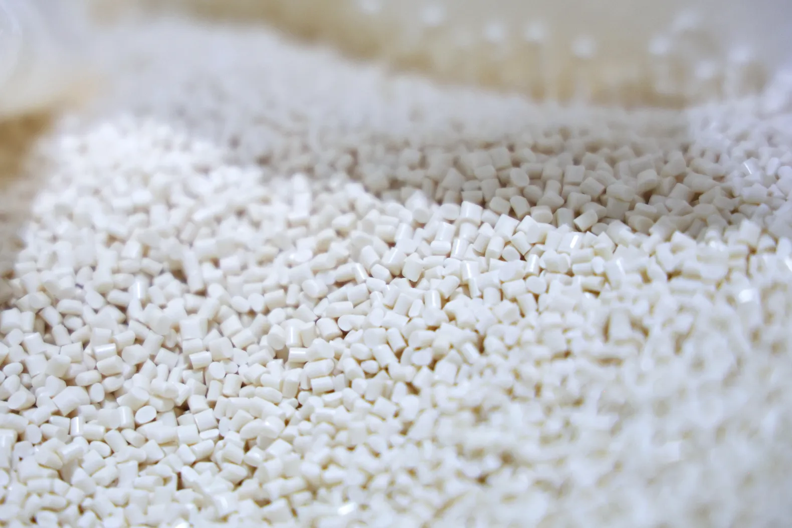 Close-up of natural-colored thermoplastic pellets used as feedstock for injection molding.