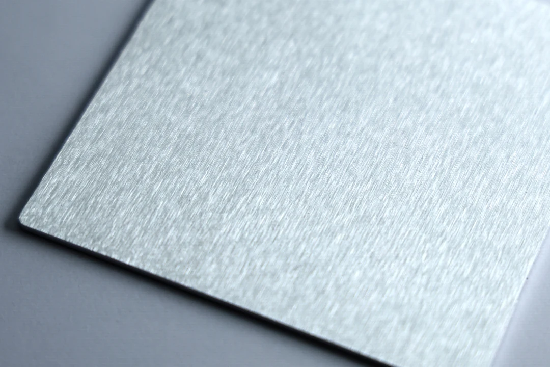 Brushed aluminum sample at 180 grit showing an even brushed grain with finer lines