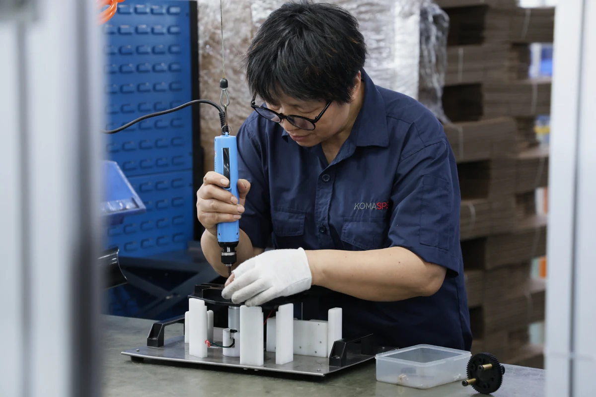 Komaspec operator using an electric torque driver at an assembly workstation with a locating fixture
