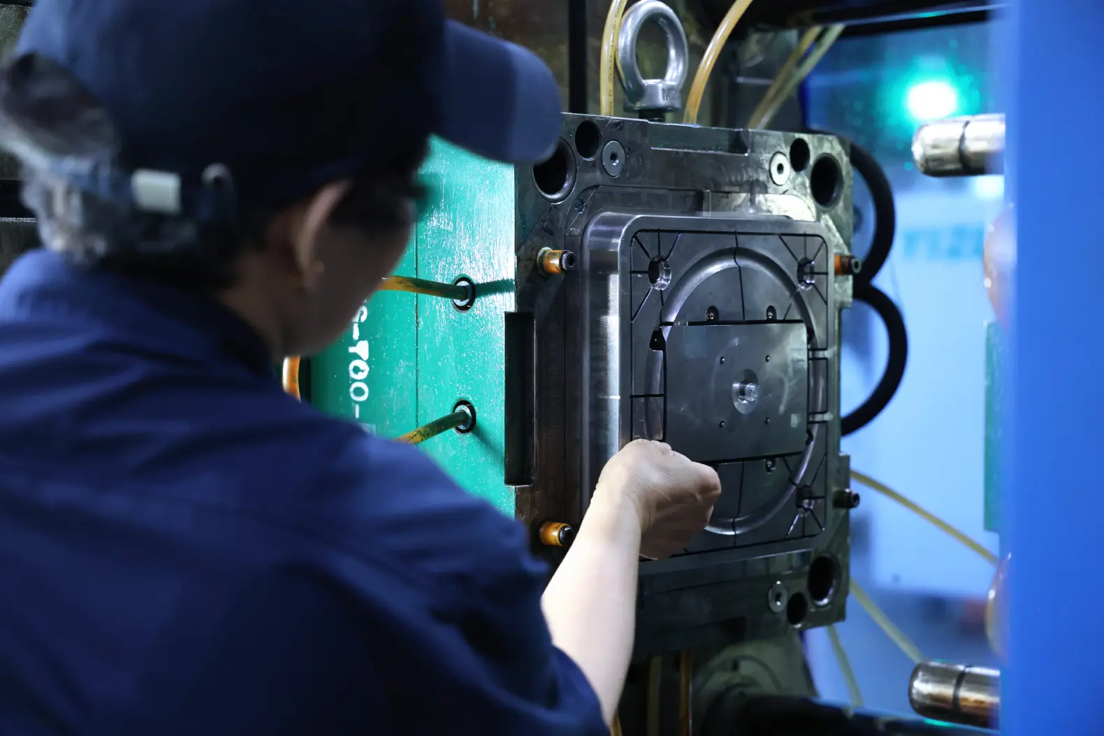 Operator loading an insert into an open injection mold on the press