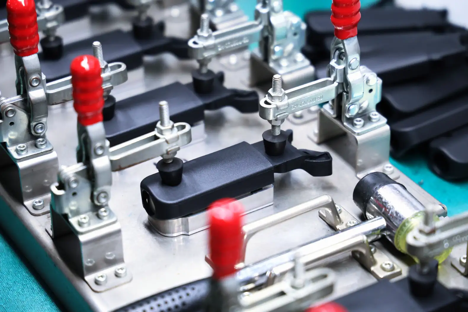 Black overmolded plastic parts held in checking fixtures with toggle clamps