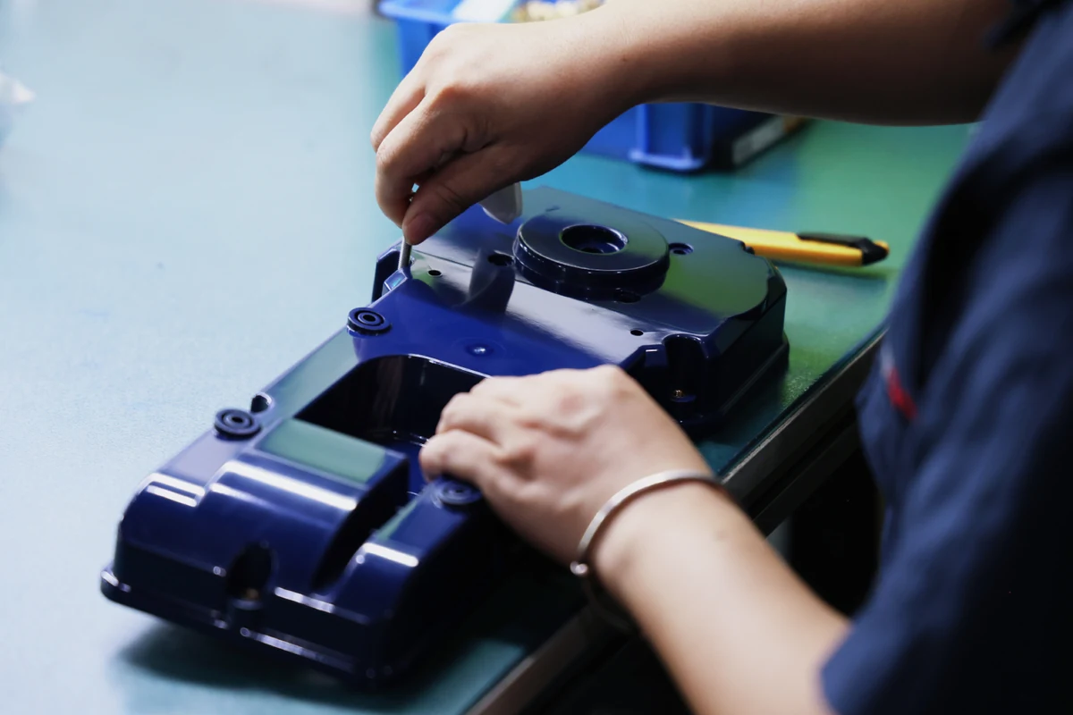 Assembler securing a screw into a threaded insert on a molded plastic equipment housing