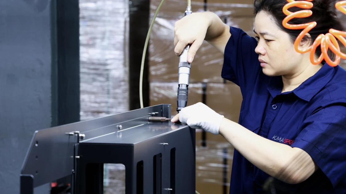Technician fastening a sheet metal enclosure panel with a pneumatic tool