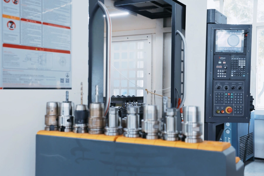 CNC machine control panel beside a yellow rack holding cutting tools.