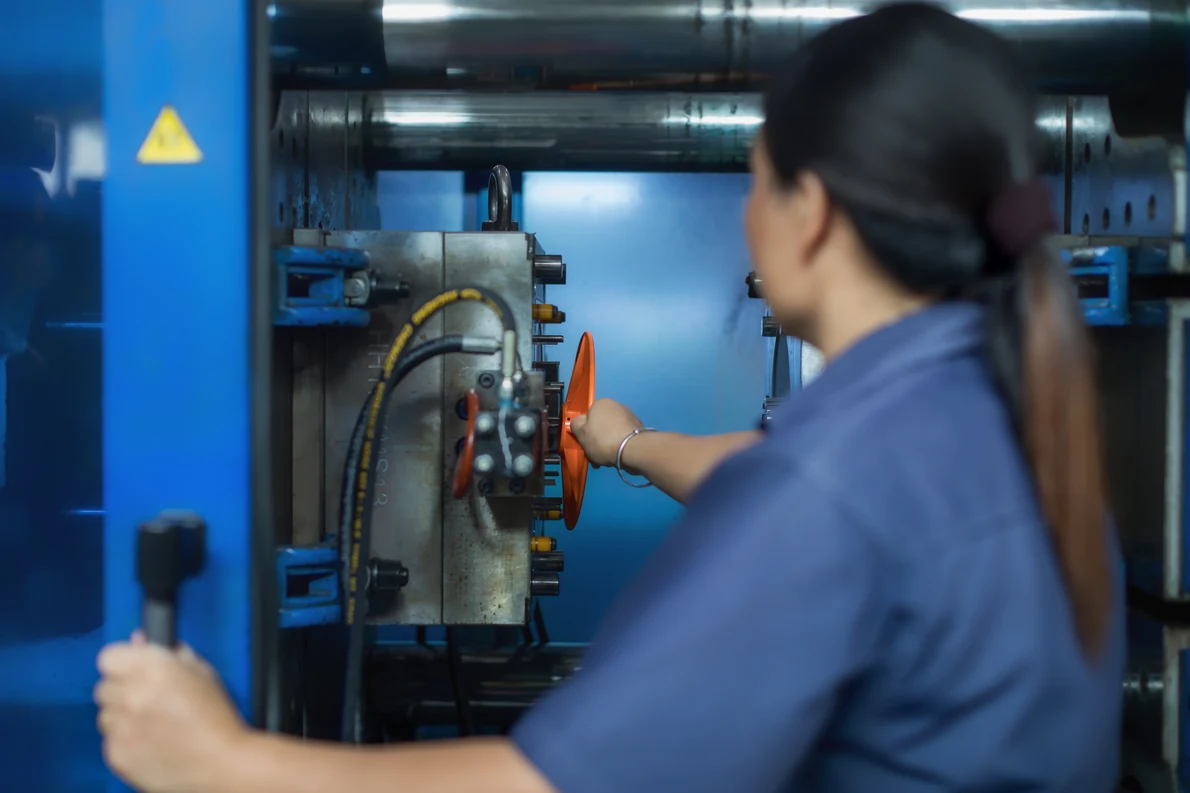Technician adjusting tooling components on an injection molding machine during setup