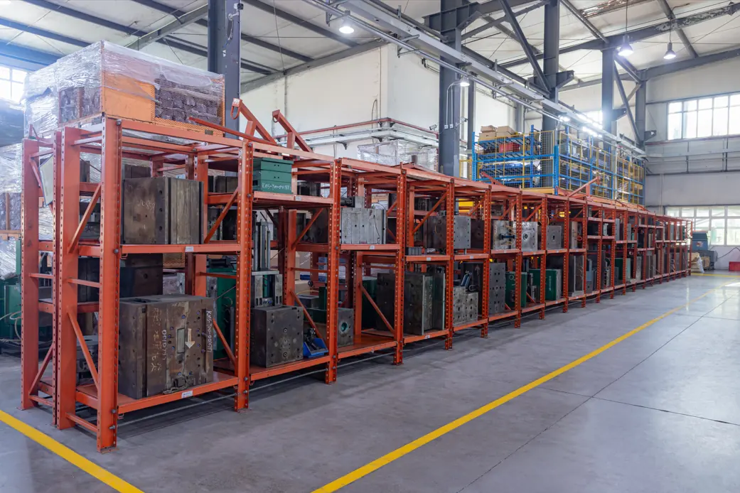 Steel injection mold tools stored on orange racking in a manufacturing facility