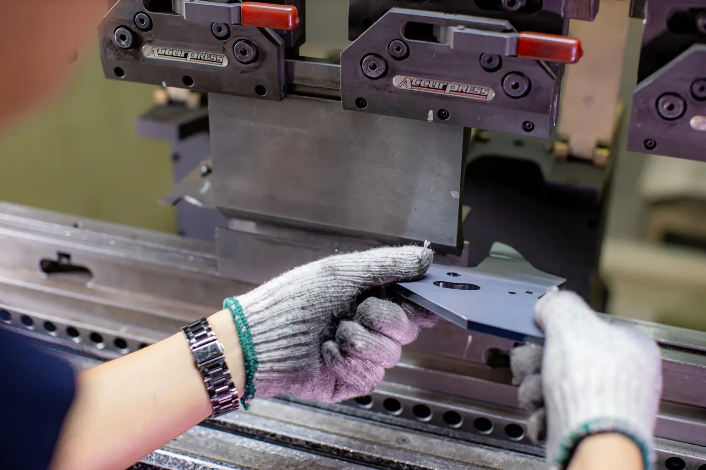 A worker feeding sheet metal into a press brake