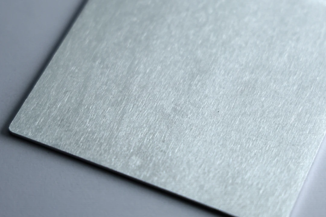 Brushed aluminum sample at 320 grit showing a soft, low-contrast brushed grain
