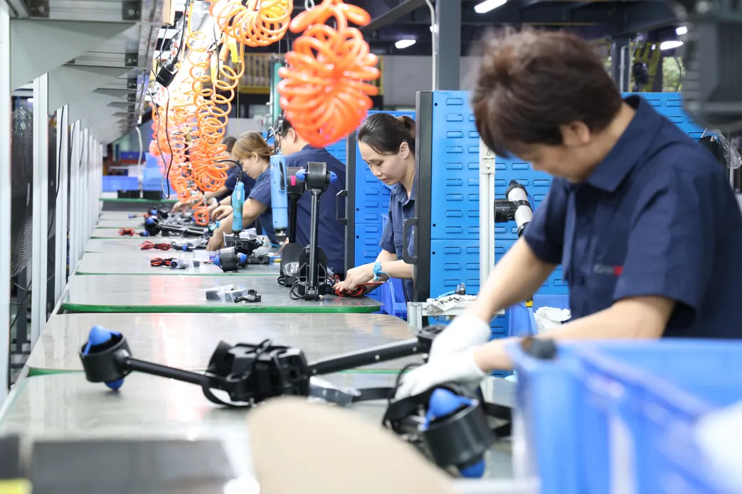 Workers assembling overmolded handle assemblies on a production line