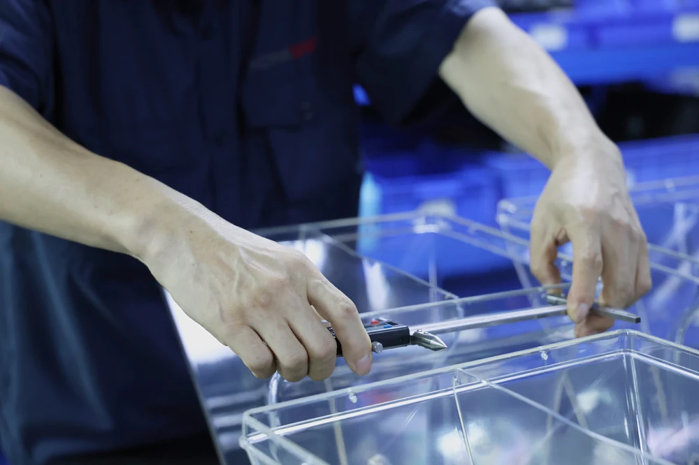 Operator inspecting clear injection molded containers at a quality control station