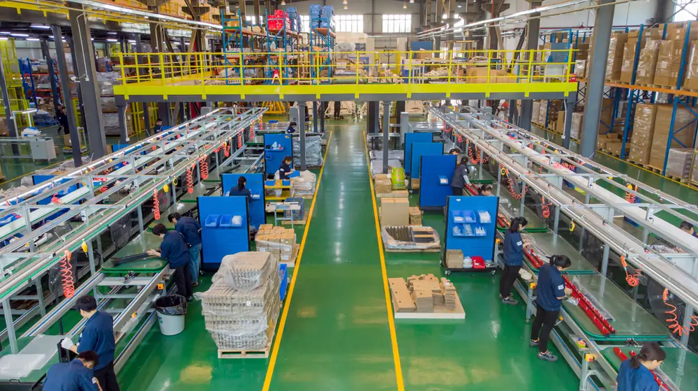 Overhead view of box build assembly lines with workstations, component racks and packed parts on the factory floor