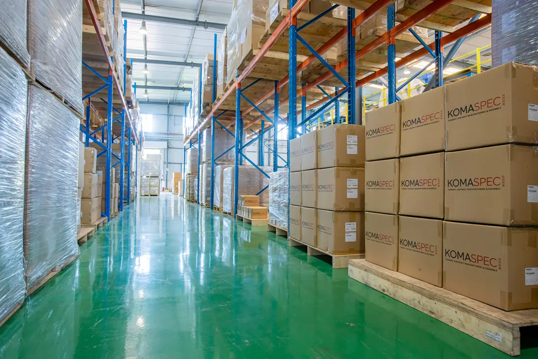 Palletised Komaspec-branded cartons of finished goods in a warehouse ready for export shipment