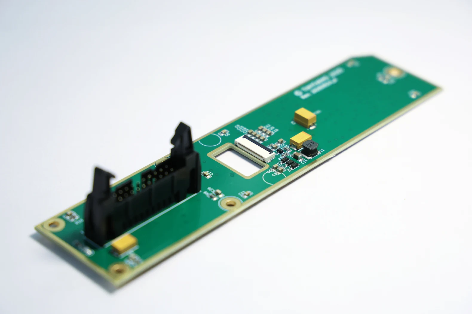 Populated printed circuit board assembly with a black ribbon connector and surface-mount components on a white background