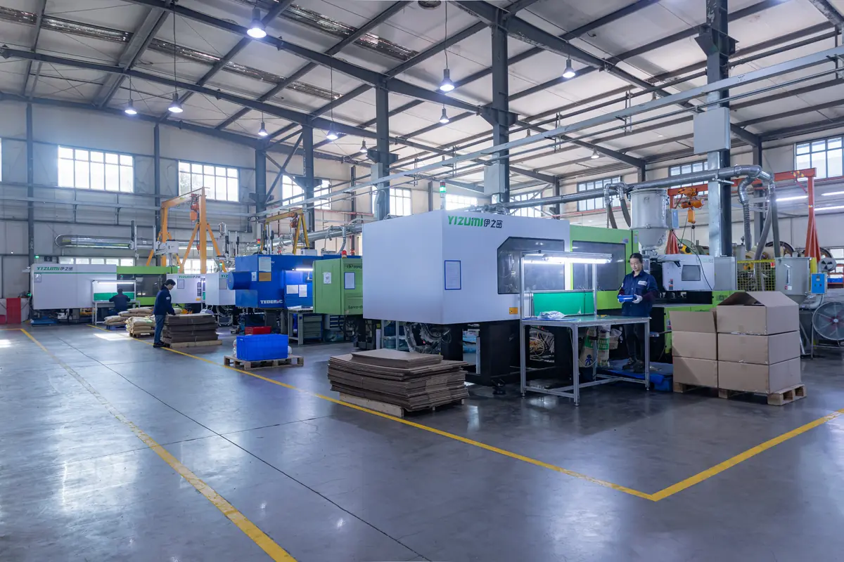 Injection molding machines on a factory production floor with an operator monitoring the press