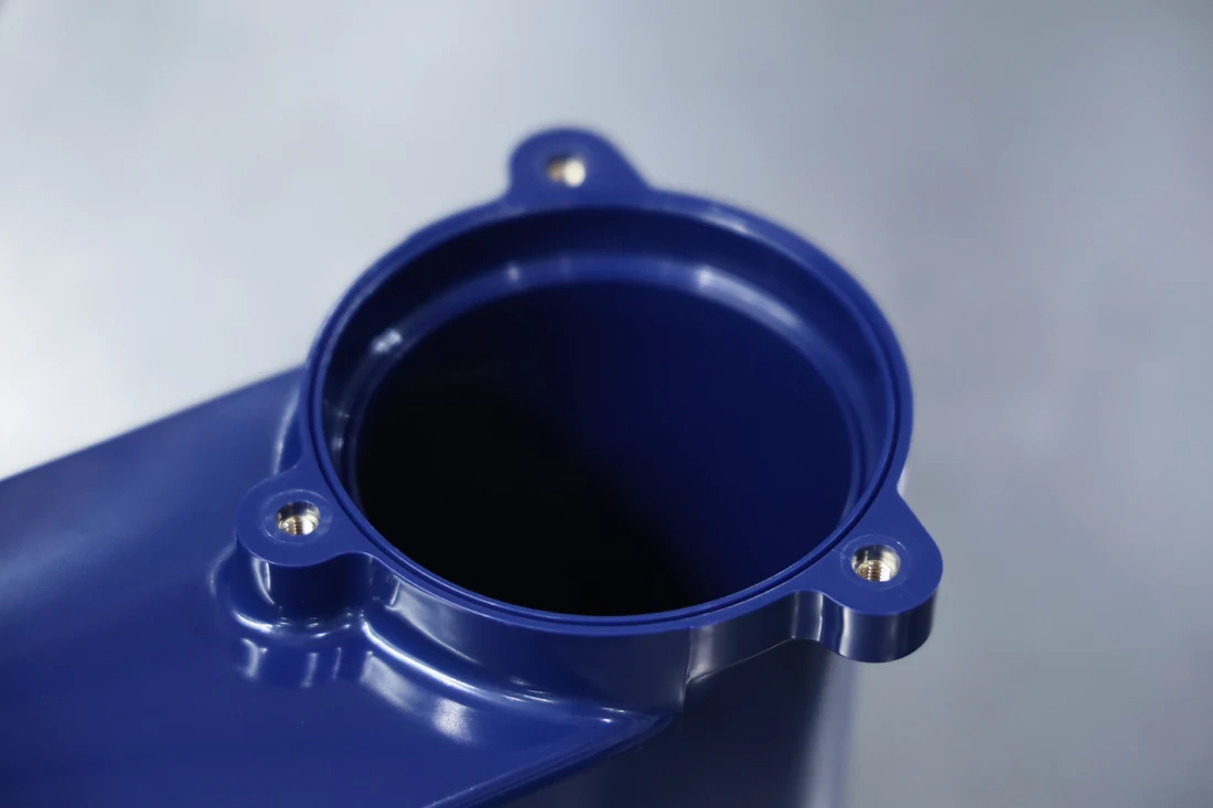 Blue insert-molded plastic housing with brass threaded inserts embedded in the mounting bosses