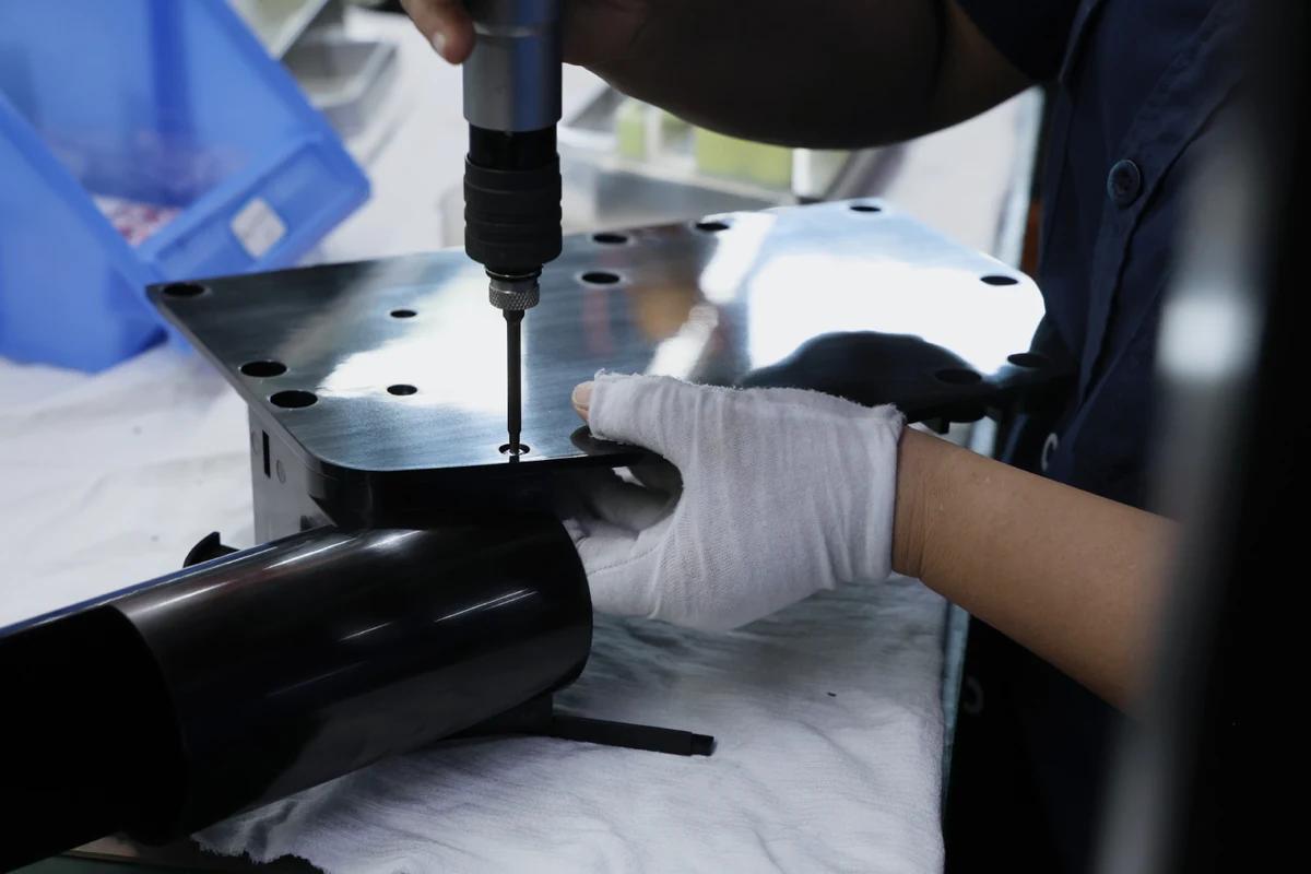 Electric torque driver fastening a black powder-coated sheet metal plate to a tube section