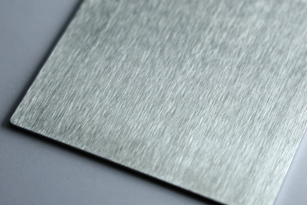 Brushed stainless steel sample at 80 grit showing coarse brush lines visible across the sheet