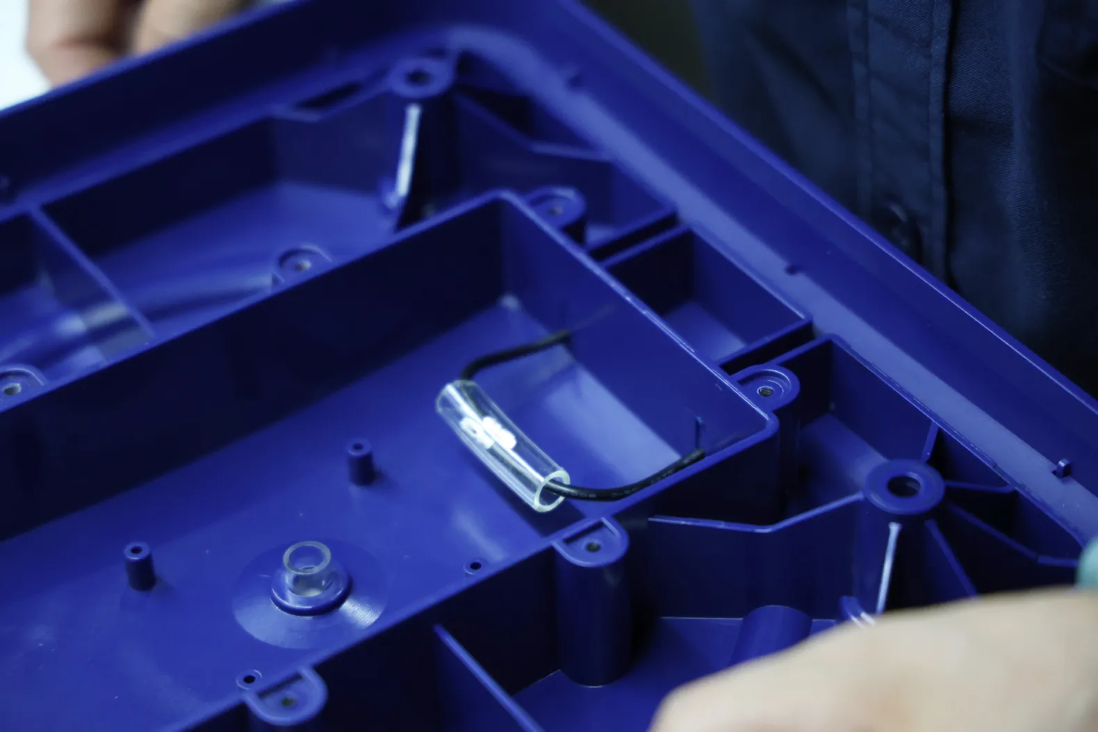 Molded plastic housing with an encapsulated cable component during production
