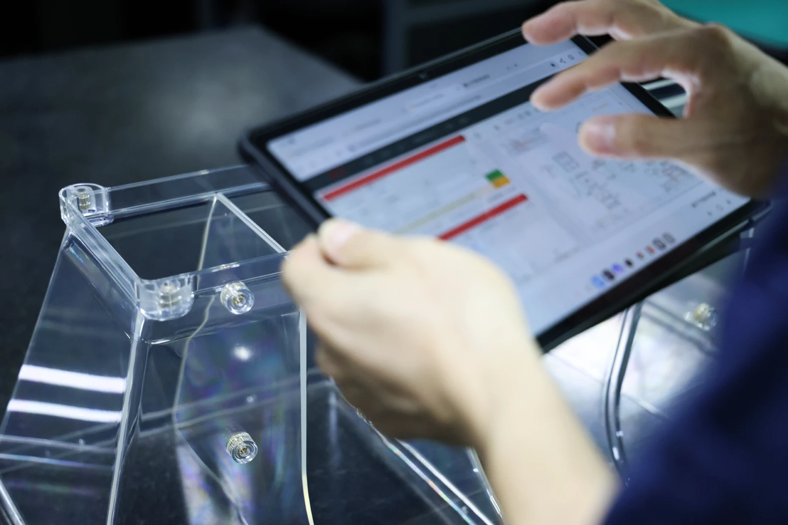 Inspector reviewing digital QC records on a tablet next to a clear plastic enclosure