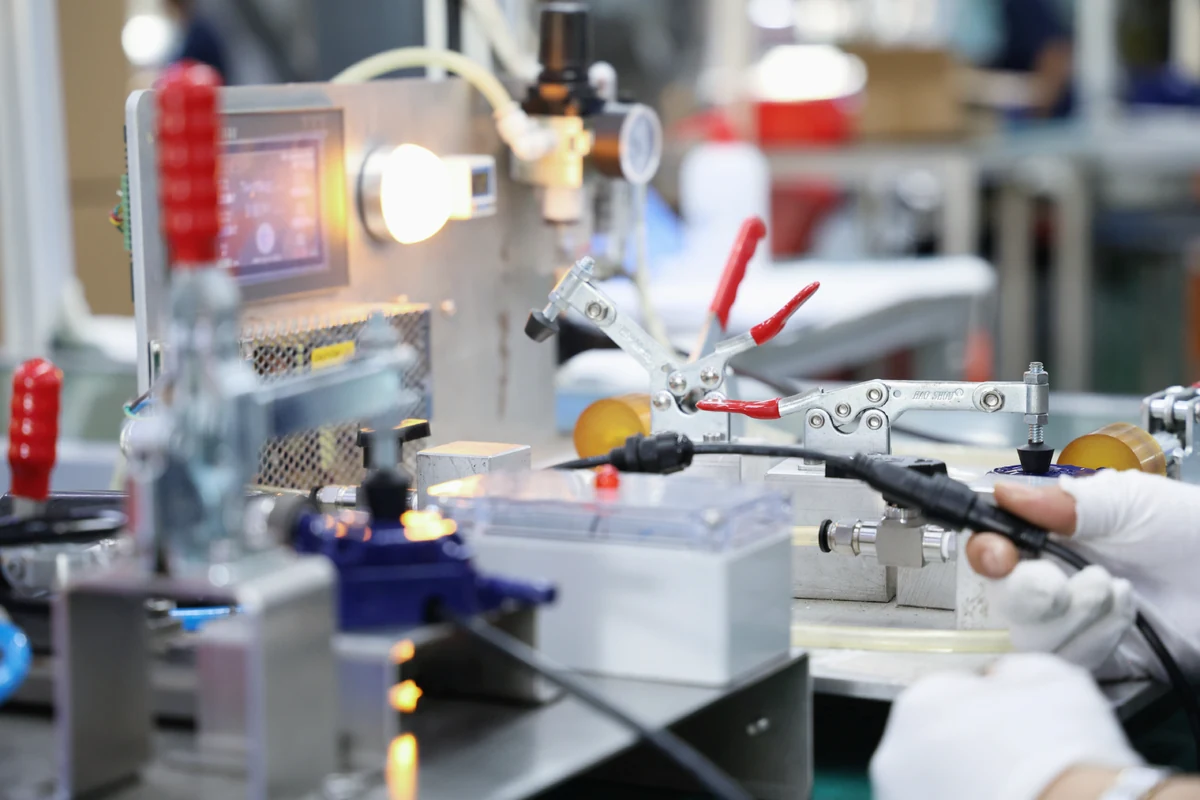 Assembly test fixture with toggle clamps holding a cable connector on a Komaspec production line