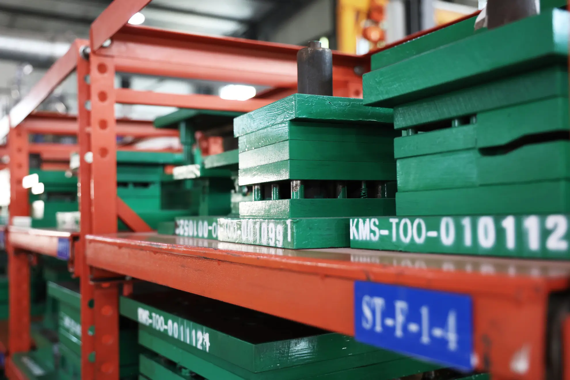 Green die sets marked with tool ID numbers stored on orange racks with location labels