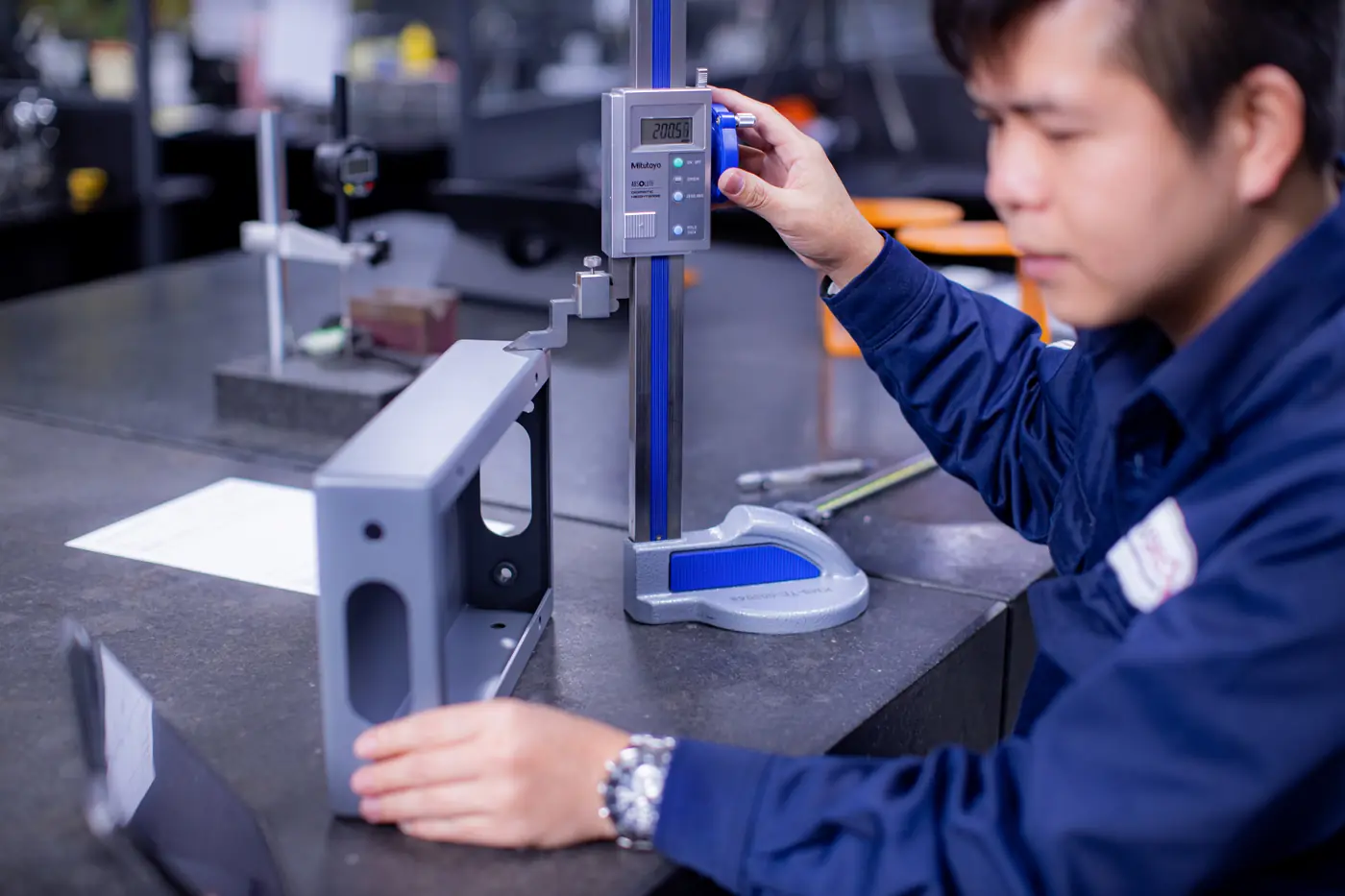 Komaspec QC inspector measuring a finished part using a precision gauge to verify it meets requirements