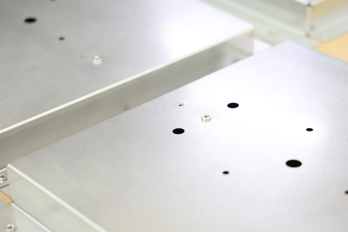 Sheet metal enclosure panels with cut-out holes and PEM clinch nut inserts