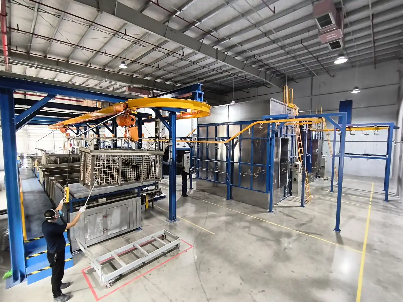 A worker operating a powder coating line at Komaspec's Vietnam facility — a key part of the company's "China Plus One" manufacturing strategy